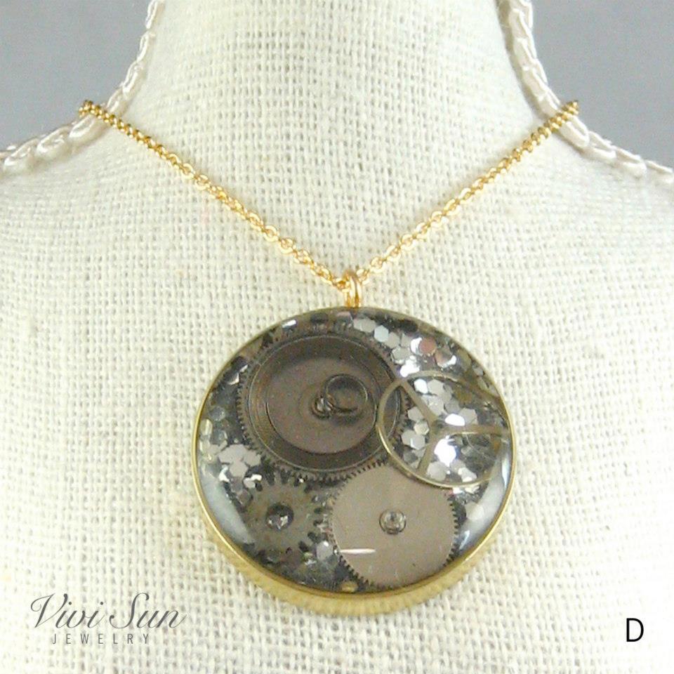 Frozen Time Necklace, 1 available (One of a kind). Donation Price: USD$42 Materials: Watch Movements, Resin, Brass & 14K Gold-Filled Chain Pendant Size: 7/8” in diameters Chain Length: Adjustable from 16” to 18”  **Note: Item appears larger in photo.